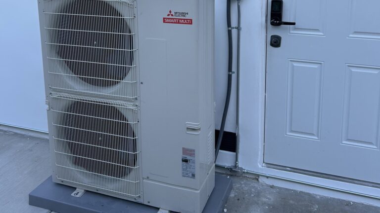 Mitsubishi Electric outdoor unit installed on a concrete pad beside a home