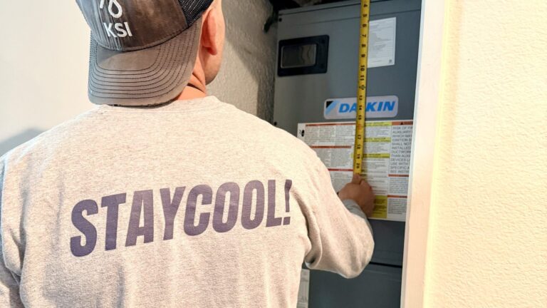 Cold Cloud technician in STAYCOOL shirt measuring a Daikin air handler for repair