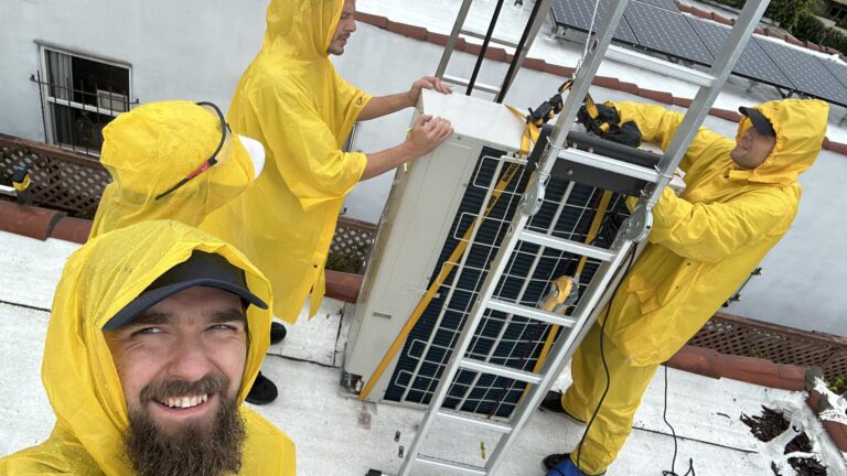 Cold Cloud crew in rain gear servicing HVAC equipment on a rooftop