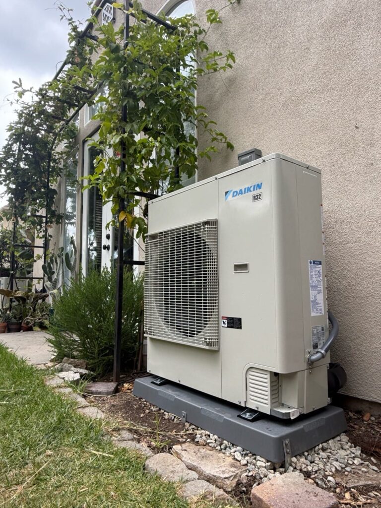 Outdoor AC unit surrounded by landscaping that can restrict airflow if not cleared