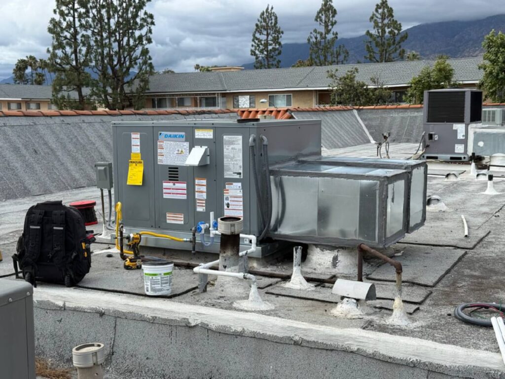 Outdoor AC condenser unit on a Los Angeles rooftop surrounded by greenery