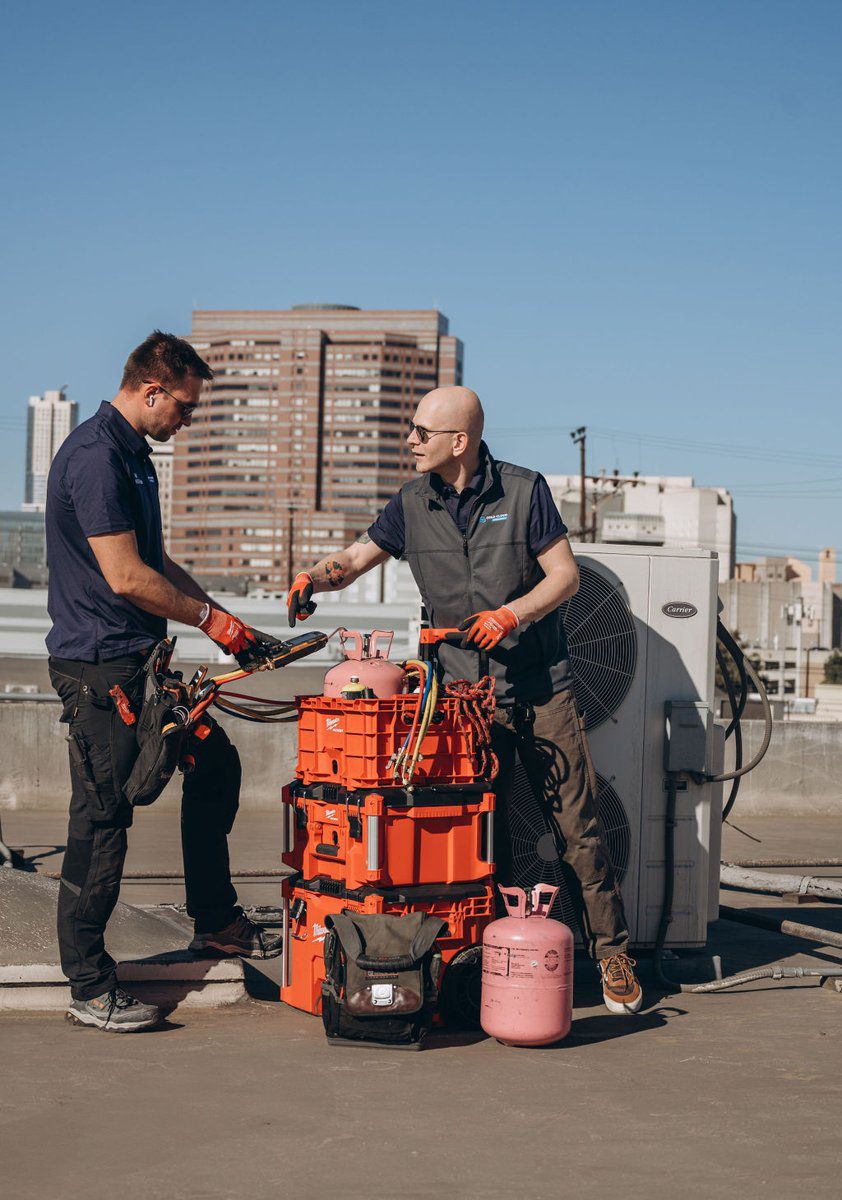 Two Cold Cloud technicians preparing tools for a rooftop HVAC job