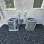 Two outdoor HVAC condenser units placed on shared gravel pad at condo building