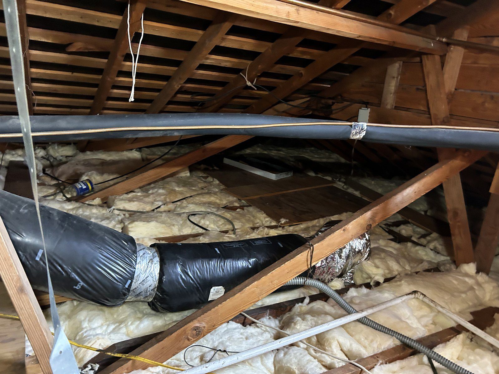 Old smoke-contaminated flex ducts lying on the attic insulation before the HVAC rebuild in Altadena, CA 91001