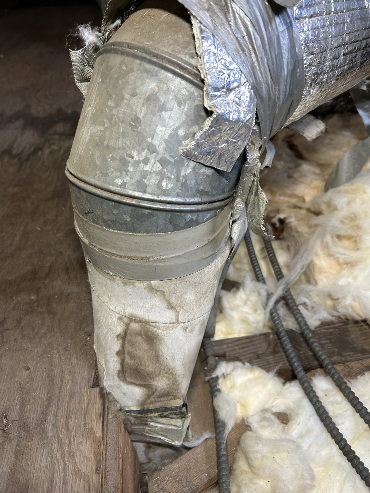 Stained old duct elbow and torn flex duct jacket in the attic before replacement in Altadena 91001